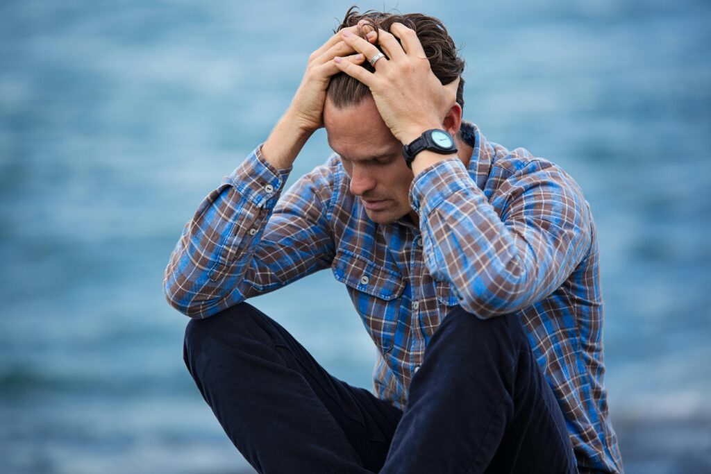 a man sitting on a rock with his hands on his head